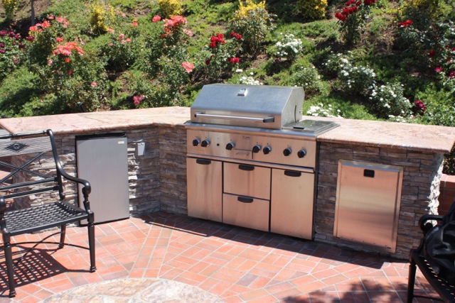 Elite outdoor grill setup with stone features and refrigerated storage