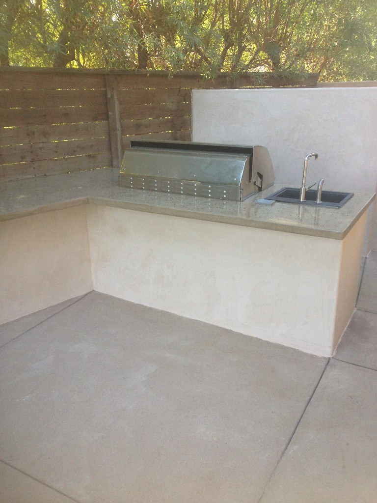 Backyard BBQ setup with concrete countertops and custom sink